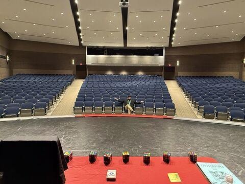 Brian Yazzie on stage in a large university auditorium with Rubik's cubes